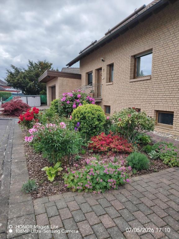 a garden of flowers in front of a house at Ferienwohnung Am Wald in Bad Marienberg