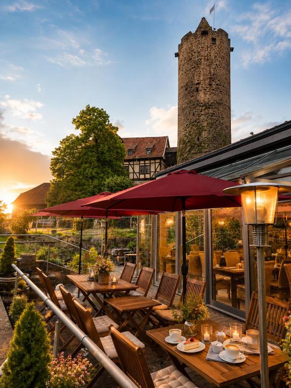 a patio with tables and chairs and a building with a tower at Hotel & Café Schachtenburg in Schlitz