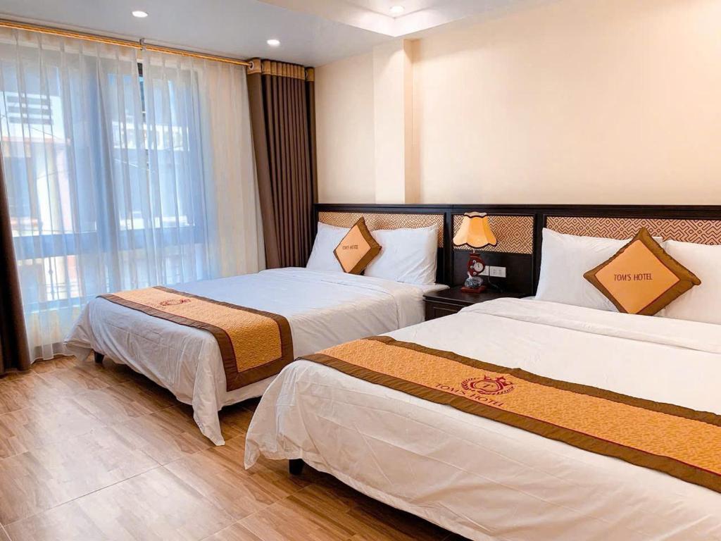 a hotel room with two beds and a window at Sapa Tom's Hotel in Sapa