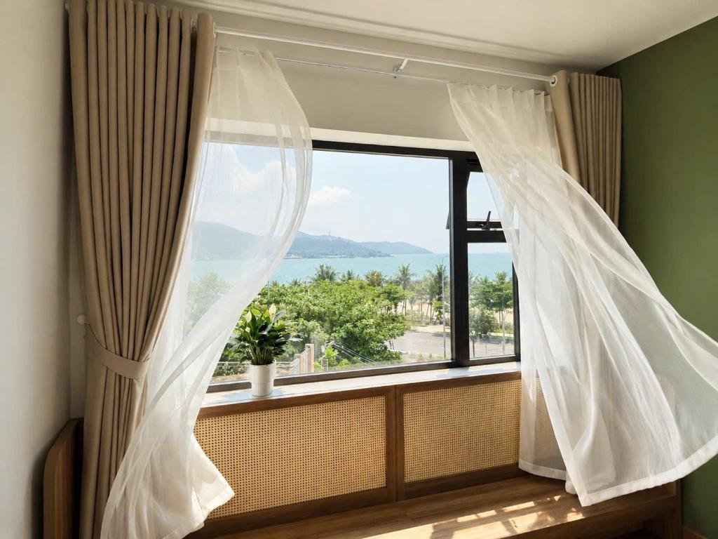 a window with curtains and a view of the ocean at An House Son Tra in Danang
