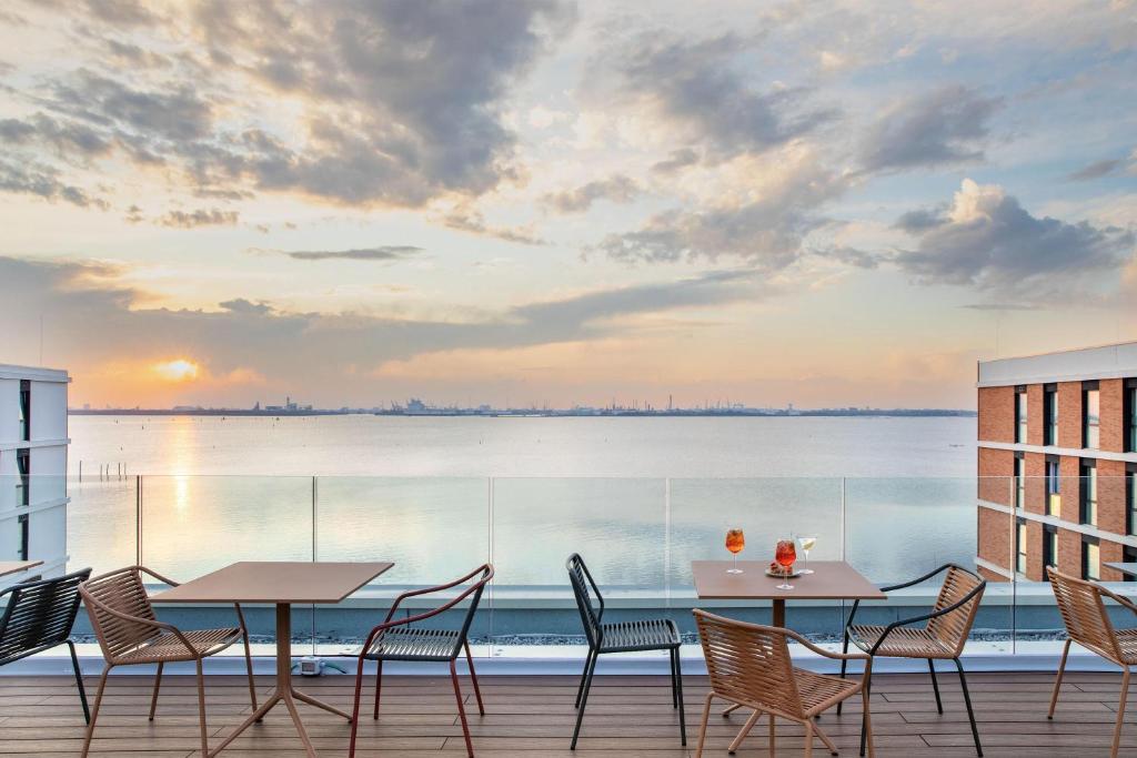 a balcony with tables and chairs and a view of the water at B&B HOTEL Venezia Laguna in Venice