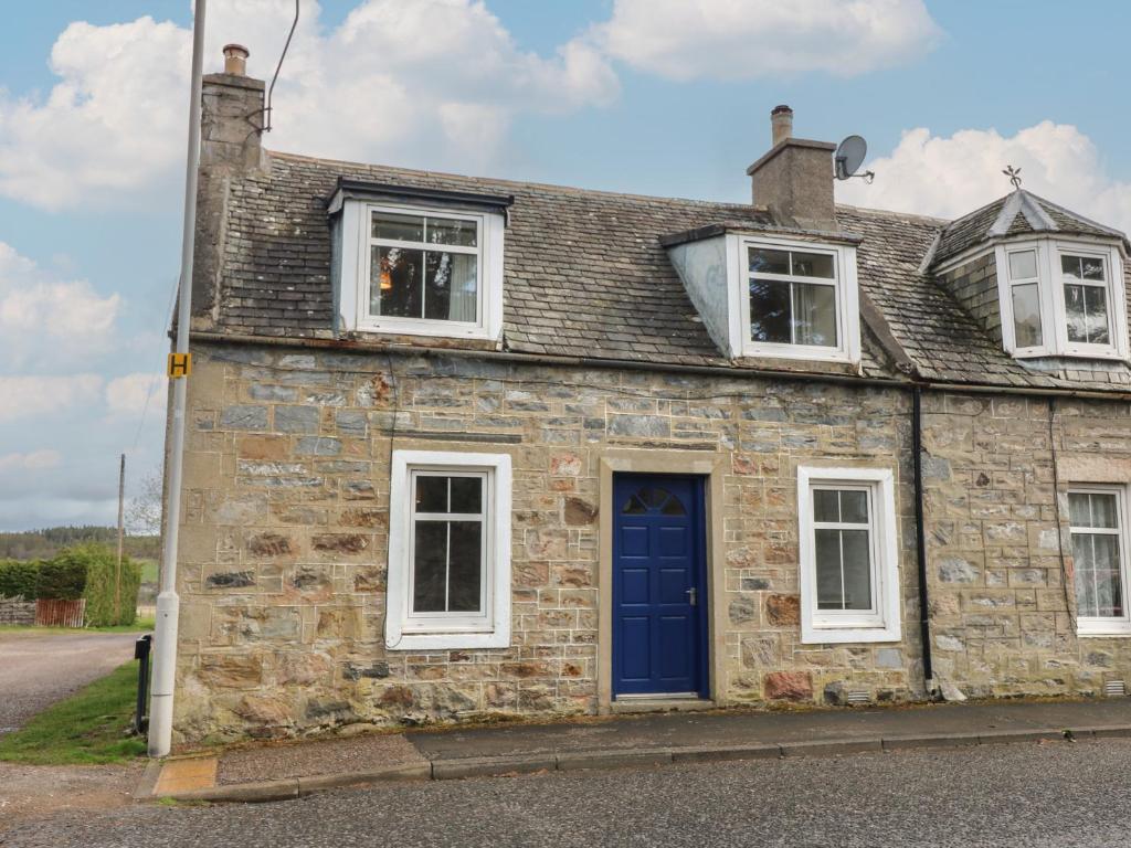 an old stone house with a blue door and windows at Alt na Voir in Tomintoul