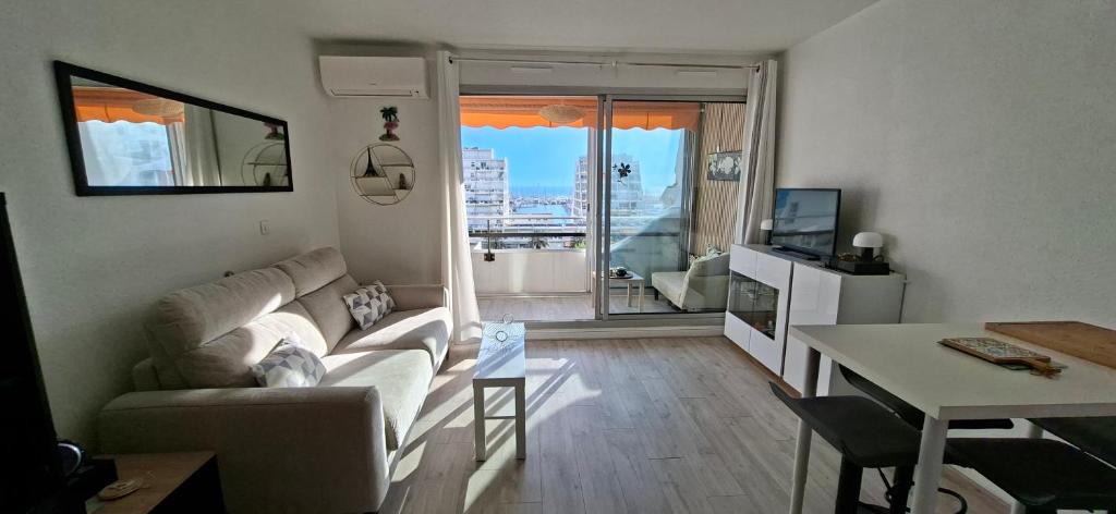 a living room with a couch and a table at Vertige Bleu, Vue mer, Port, Plage, WI-FI, Clim, Centre ville, Commerces, Calme in La Grande Motte