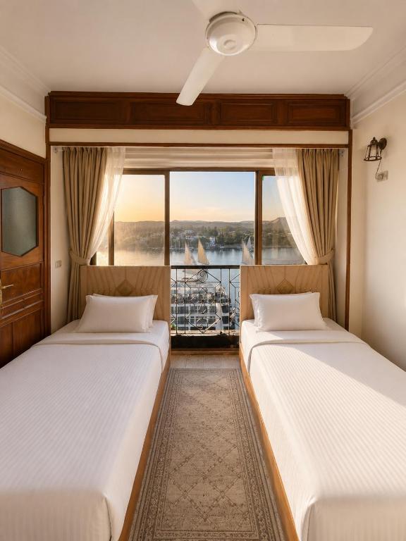 two beds in a room with a balcony at Nile View Studio Aswan in Aswan