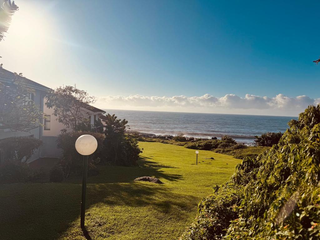 a house with a golf ball on the grass near the ocean at Rockshore at Seaverge in Port Edward