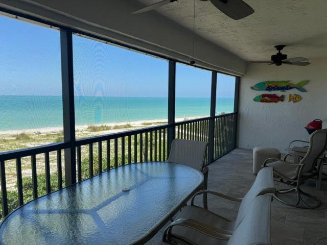 a balcony with a glass table and chairs and the beach at Sand Pointe 137 in Sanibel