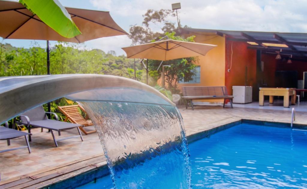 a pool with a water fountain in front of a house at Sitio Chacara Piscina Aquecida Acesso Asfaltado in Juquitiba