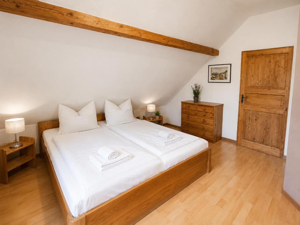 a bedroom with a large white bed and wooden floors at Ferienwohnungen auf Reiterhof in Kevelaer in Kevelaer