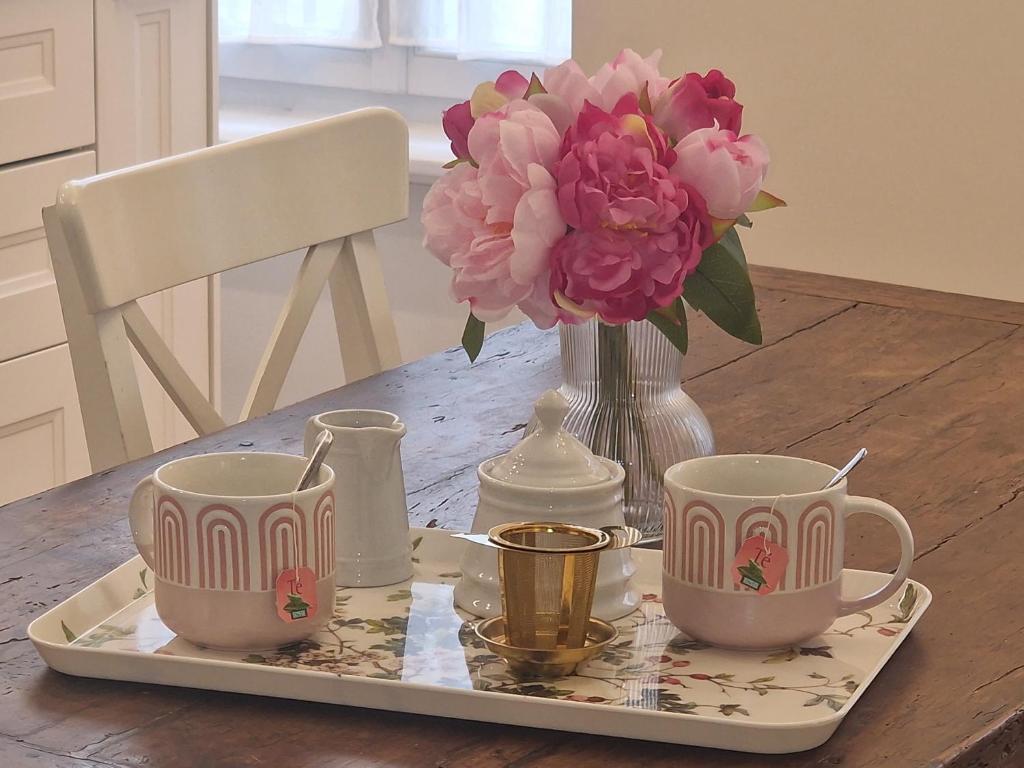 a tray with two cups and a vase with pink flowers at Maison de Centre ville in Limoux