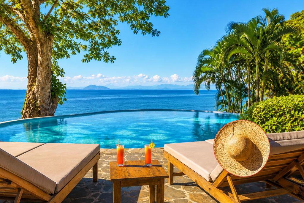 a pool with a table and chairs next to the ocean at Manga Soa Lodge in Fascène - Befefika