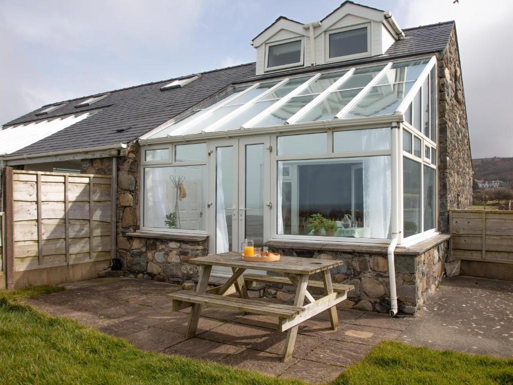 a glass house with a picnic table in front of it at Hayloft - Ukc4678 in Clynnog-fawr