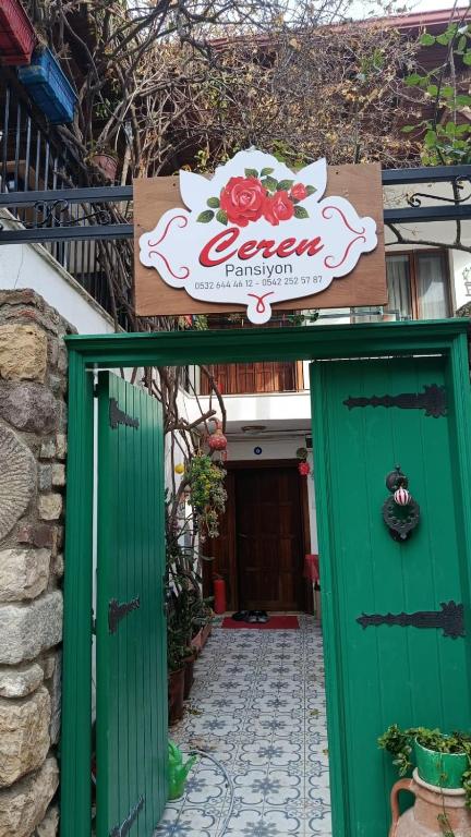 an entrance to a house with green doors and a sign at Ceren pansiyon in Seferihisar