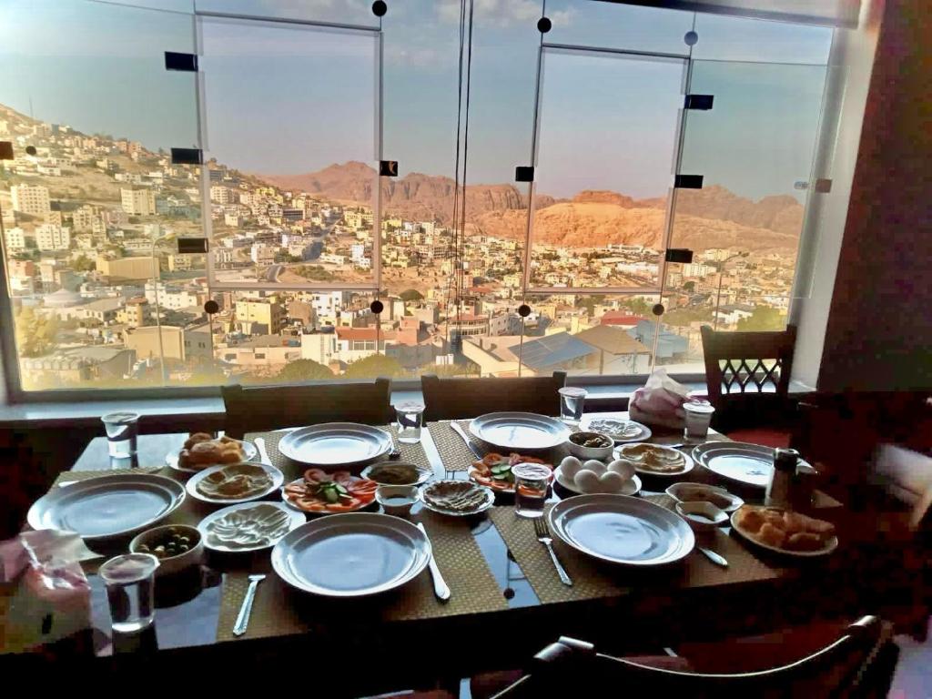 a table with plates of food and a view of a city at فندق دير البتراء السياحي in Wadi Musa