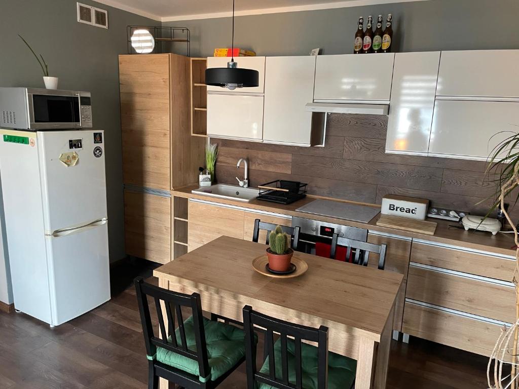 a kitchen with a table and a white refrigerator at Apartament pod dębami in Trzcianka
