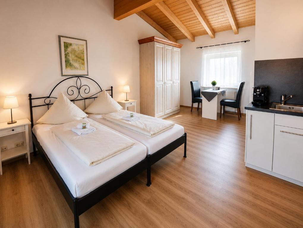 a bedroom with a bed with a kitchen and a table at Dorfschänke DEGGENDORF Hotel & Apartmenthaus in Deggendorf