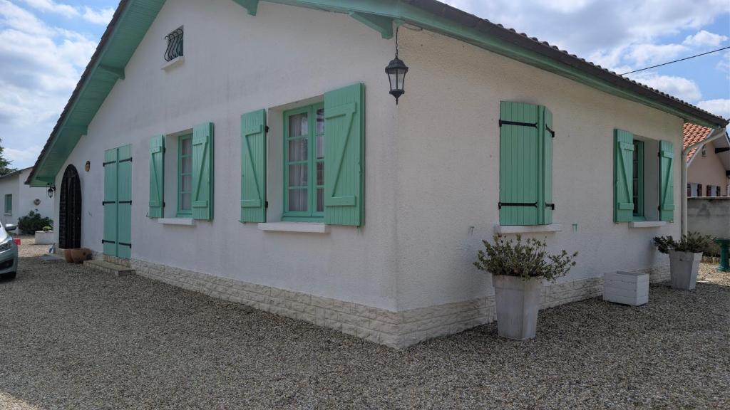 a white building with green shutters on it at Marychris in Saint-Loubès