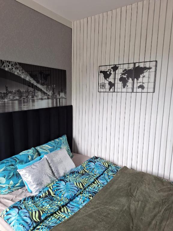 a bedroom with a bed with blue sheets and a wall at Noclegi 2 pokoje in Szczecinek