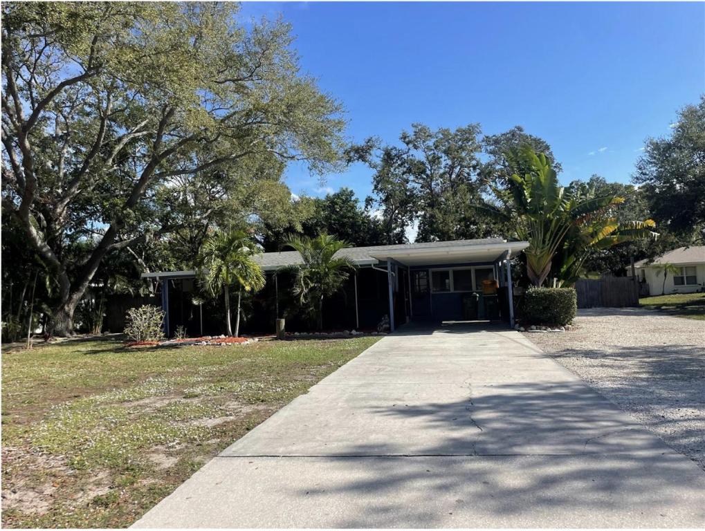 a house with a porch and a driveway at Indian Beach Cottage in Sarasota