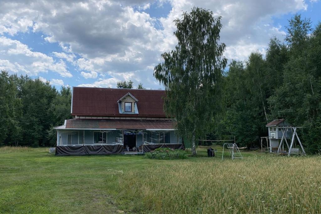 a house with a red roof in a field at Malinada-kaimo sodyba in Šalčininkai
