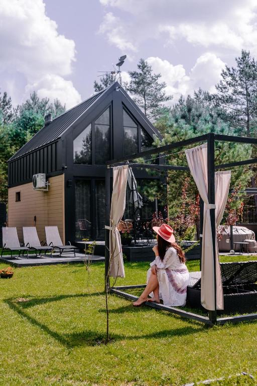 a woman sitting on the grass in front of a house at Villa Pino in Borsk