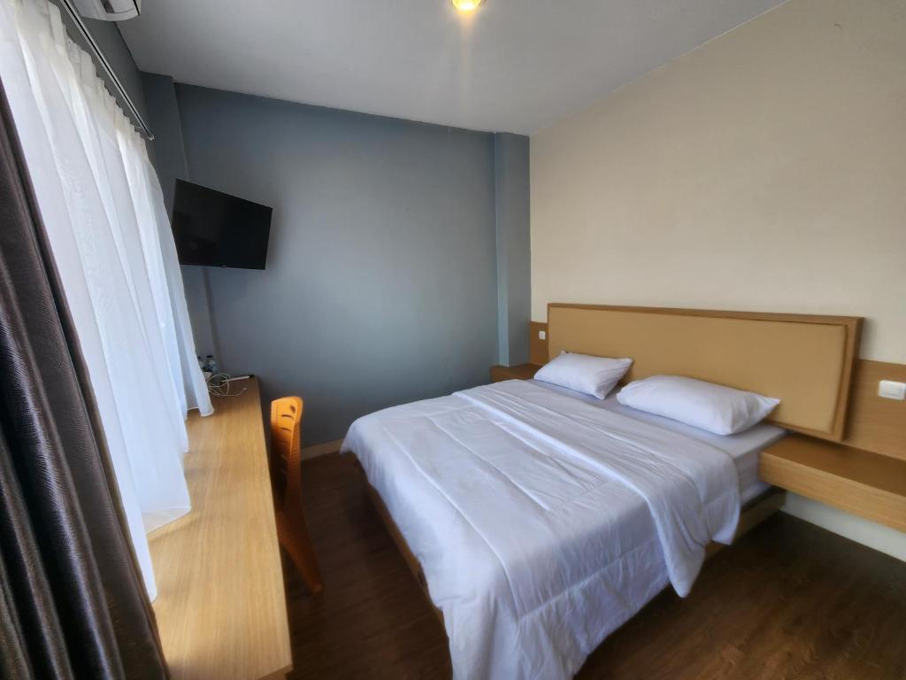 a small bedroom with a bed and a television at Sendja Residence in Semarang