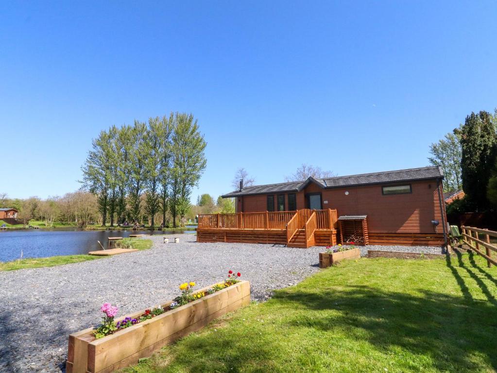 a house by the water with flowers in a yard at Lakeside Lodge in Preston