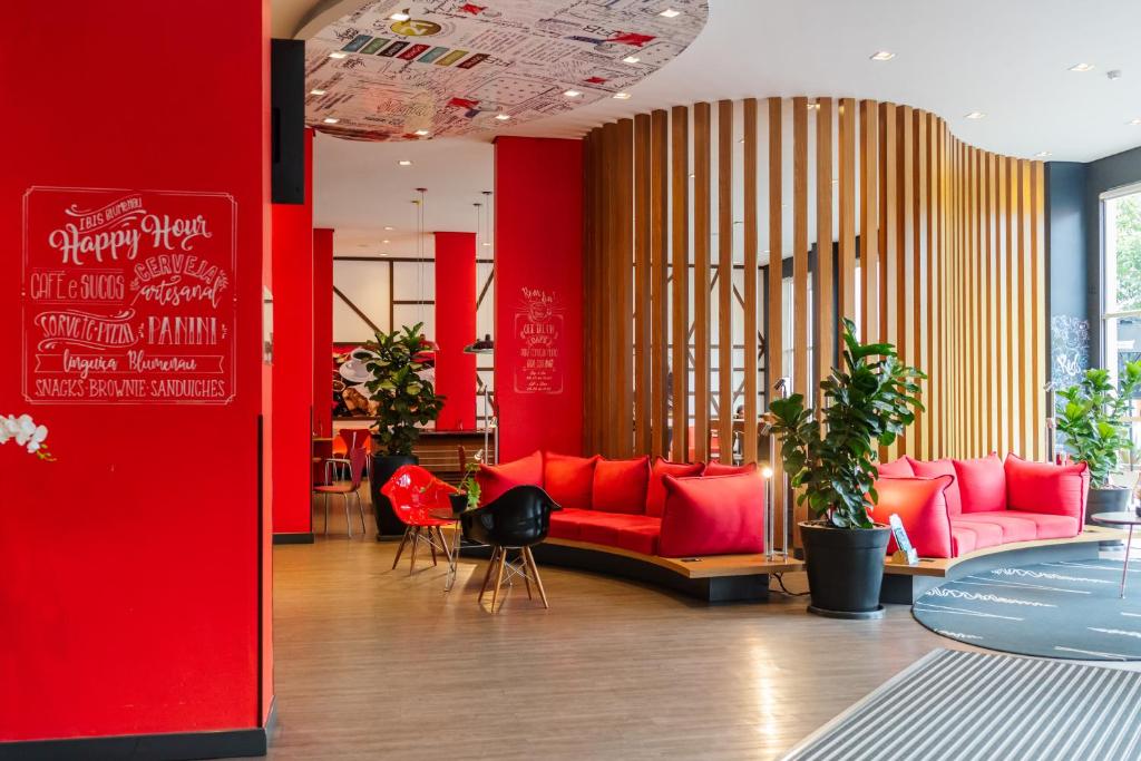 a room with red couches and a red wall at ibis Blumenau in Blumenau