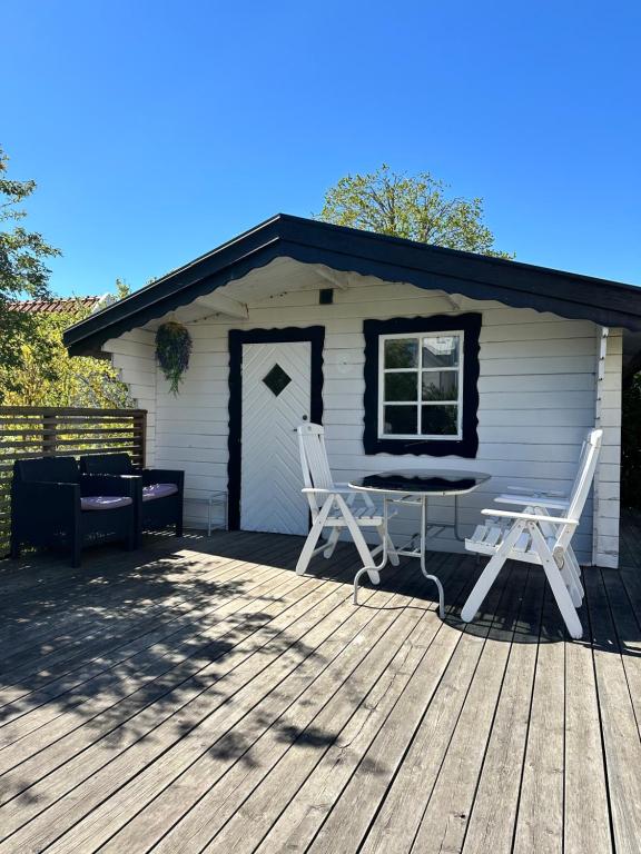 a house with two chairs and a table on a deck at Mysig stuga i lugnt villaområde med eget badrum och kök i huvudbyggnadens källare in Kalmar