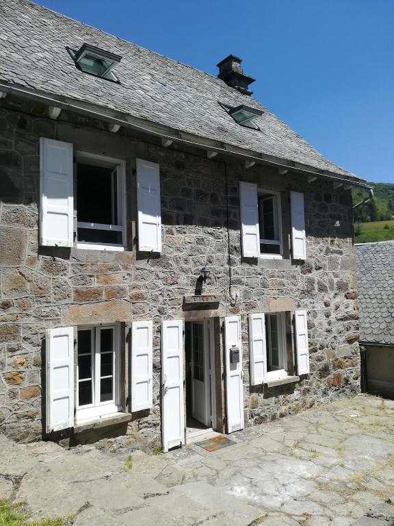 an old stone building with white doors and windows at Maison typique auvergnate in Saint-Jacques-des-Blats