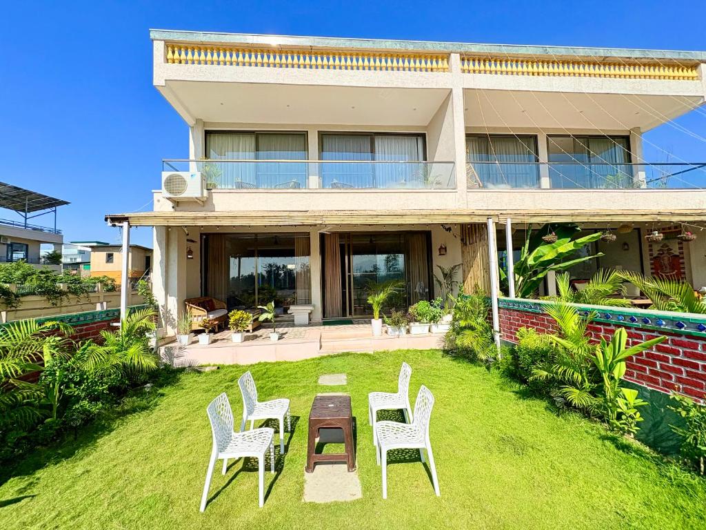 a house with two chairs and a table in the yard at Eternal Bliss By Ganga Blessing in Rishīkesh