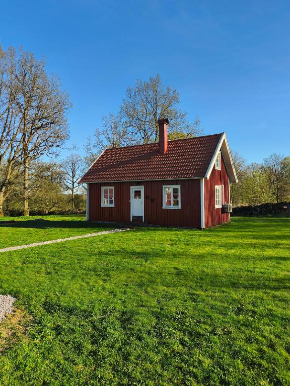 a red house in a field with a green yard at The Red Butterfly 2 cottage in Månstad