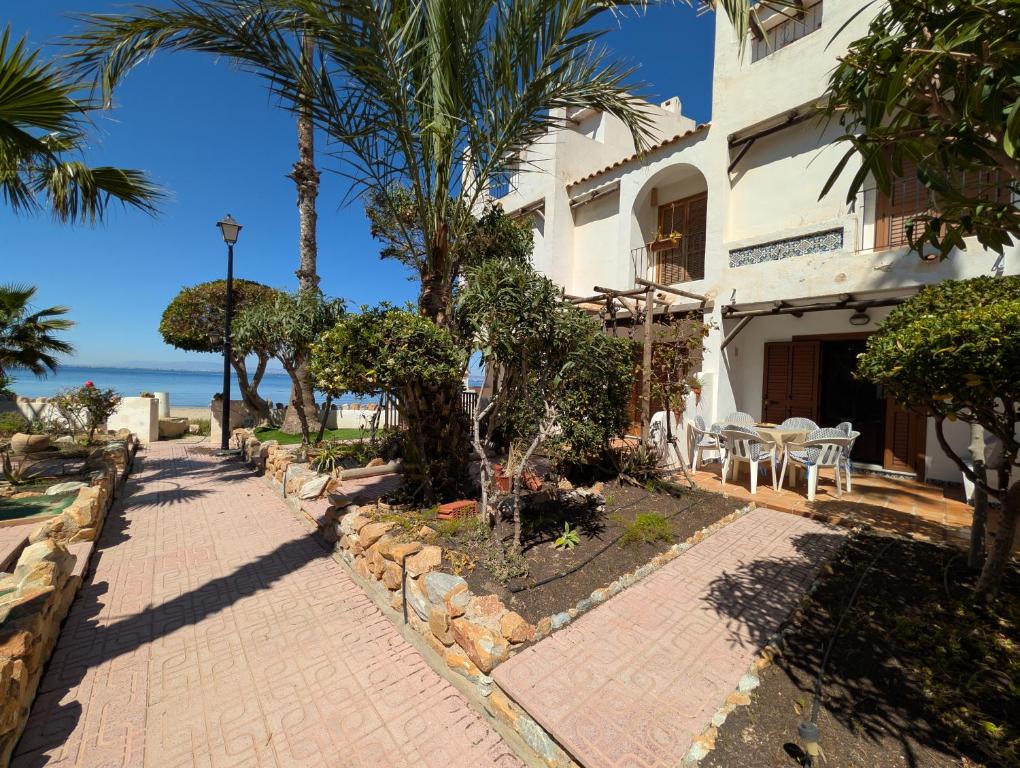 a building with palm trees in front of the ocean at Jardín secreto del Mar Menor, La Manga in San Javier