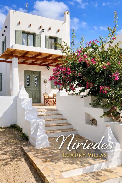 a white house with pink flowers on the stairs at Niriedes Villas in Leipsoi