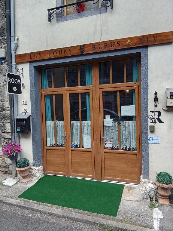 a door to a store with a green mat in front at Room - Les loups bleus in Rossillon