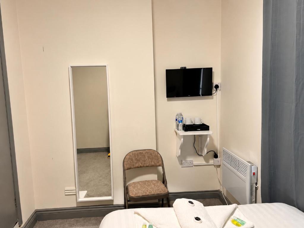a room with a mirror and a bed and a chair at 18 Budget Inn in London