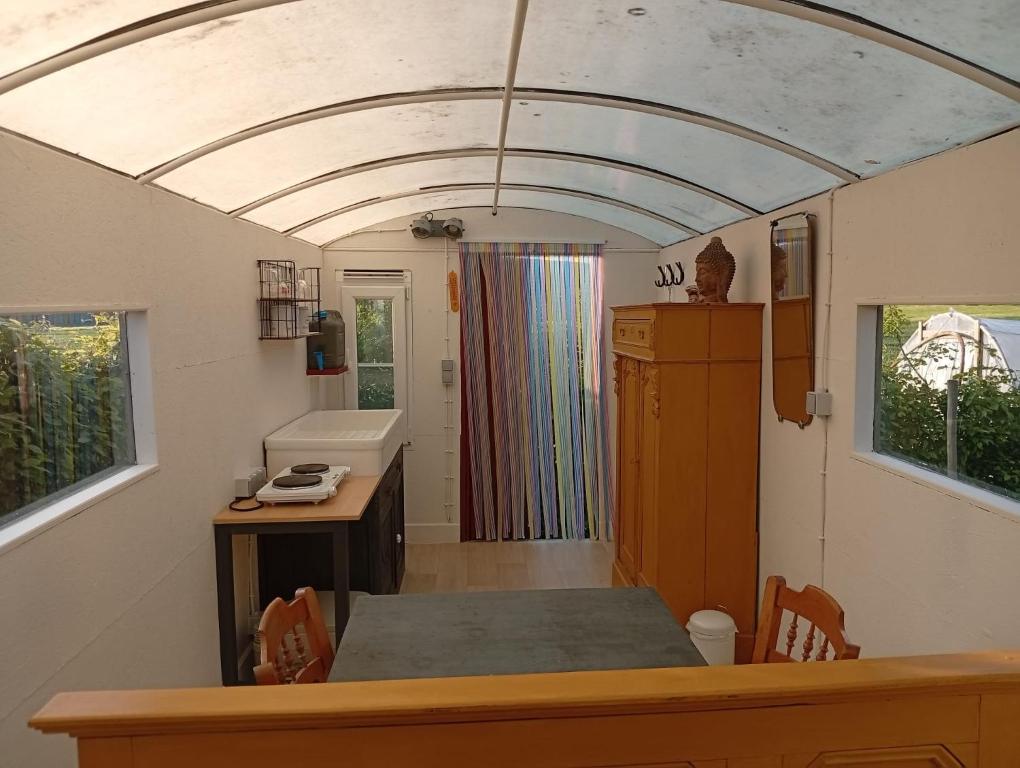 a room with a table and a kitchen with a window at De smishoeve "Herdershut" in Heers