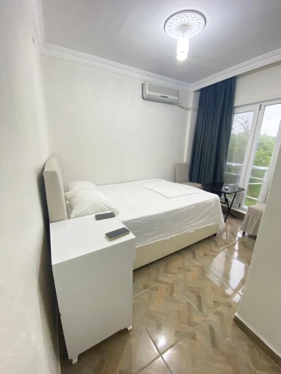 a white bedroom with a bed and a desk at AirPort geust house in Arnavutköy
