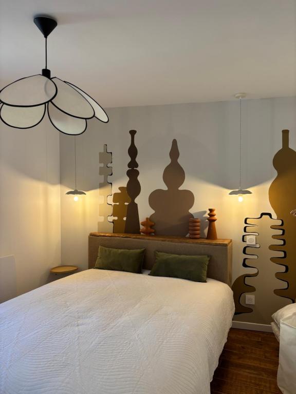 a bedroom with a white bed and a chandelier at Nid d argile - appartement neuf - 650m des Thermes - 1er étage in Salins-les-Bains