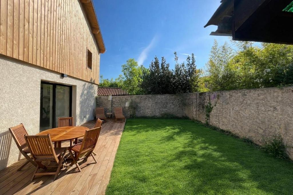 a patio with a wooden table and chairs on a lawn at Le Petit Chalet in Crolles