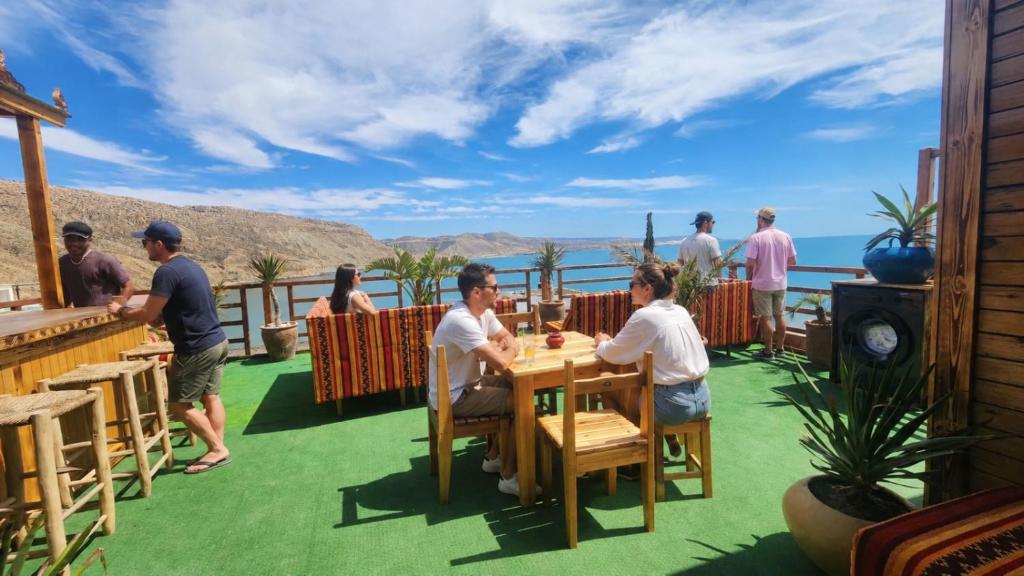 a group of people sitting at a table on a deck at Padova Surf Hous in Imsouane
