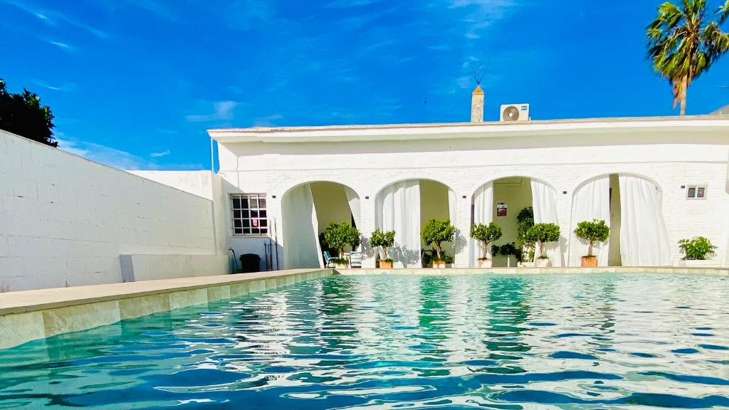 a swimming pool in front of a white building at Villa Estrella in Dos Hermanas
