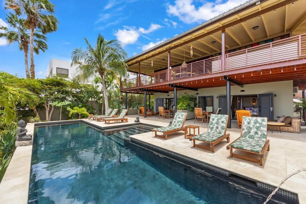 a swimming pool with chairs and a house at Bali Suites - Sanur suite in Willemstad