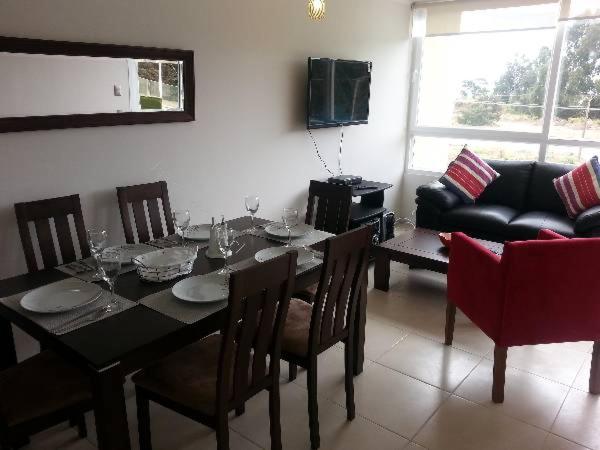 a dining room with a table and chairs and a couch at Condominio Lomas de Papudo I in Papudo