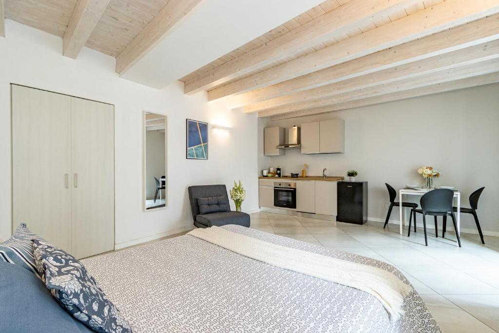 a white bedroom with a bed and a kitchen at Al Castello - fresco e ben isolato appartamento in Calolziocorte