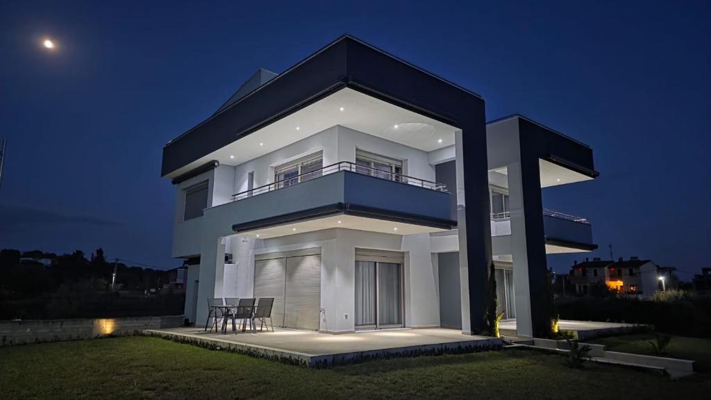 a large white house with two chairs in front of it at Pearl Luxury Suites in Paralia Dionysiou
