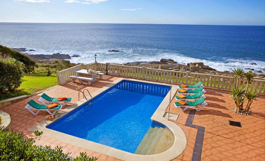 a swimming pool with chairs and the ocean in the background at Villa Rosal in Oia