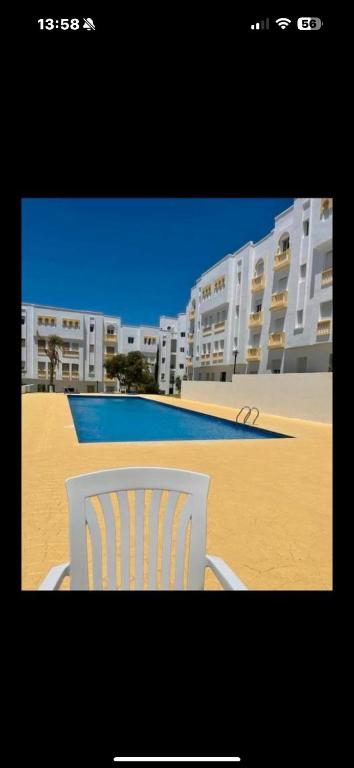 a white chair sitting in front of a building at L Escale de l Atlantique Dar Salma fibre optique piscines,clim&parking in Tangier