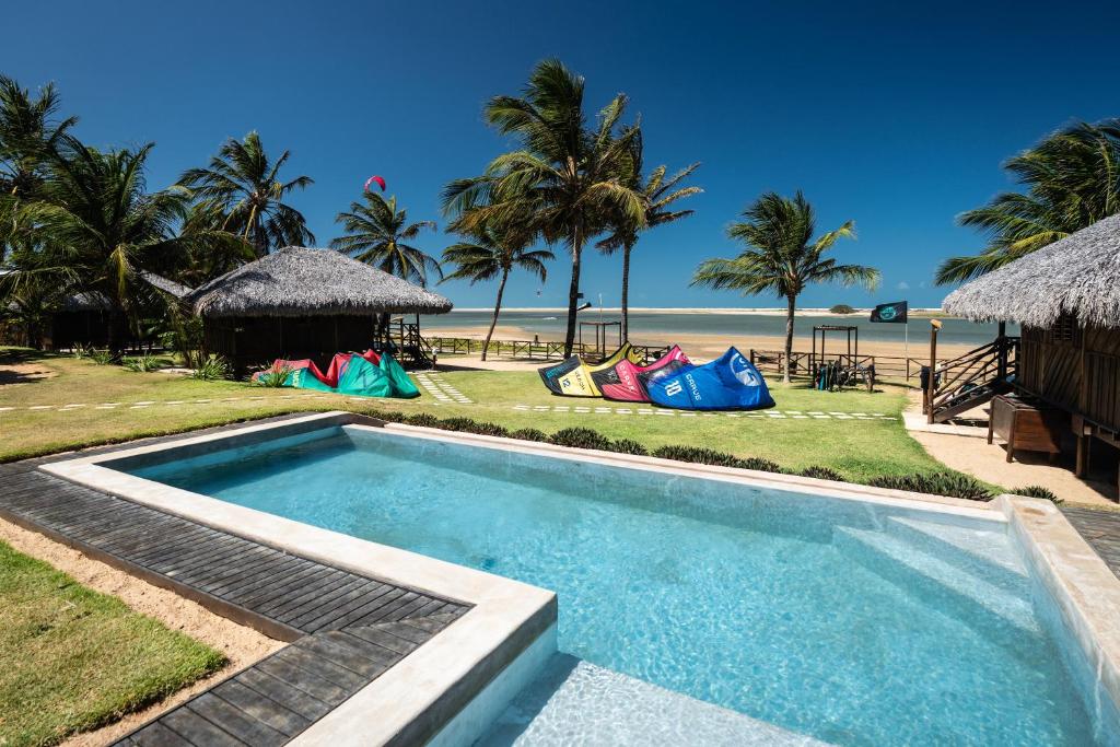 a swimming pool next to a beach with palm trees at Pousada Casa Suiça in Itarema