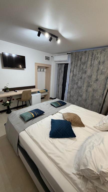 a bedroom with a large bed with blue pillows on it at Micul Cosmopolit Boutique Rooms in Afumaţi
