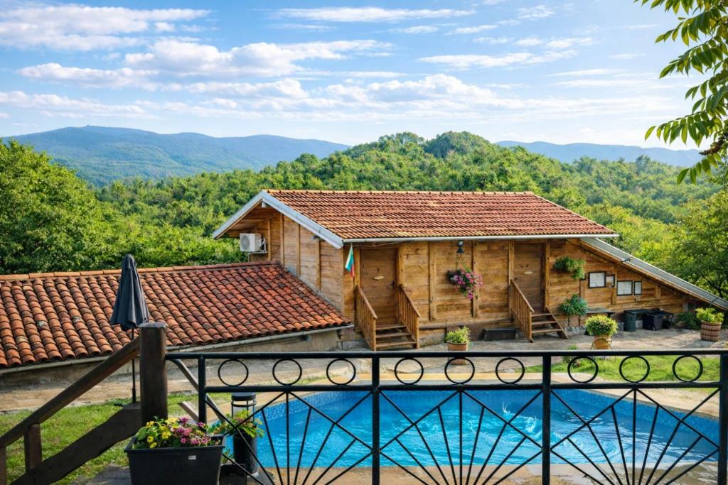 a log cabin with a pool and mountains in the background at Guest House Kandaferi 2 in Elena